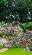 A group of people sitting on a lawn at Plantation Garden Norwich