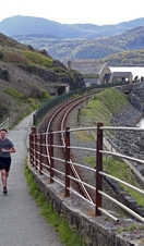 Two people running along a coastal path in Wales