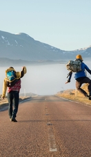 Rear view of two men jumping with joy on a country road 