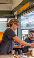 A woman serving drinks at a stall in Norwich Market