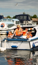 A family riding on a boat in the Norfolk Broads