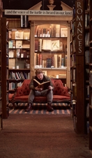 Man sitting on a sofa, reading a book at a bookshop
