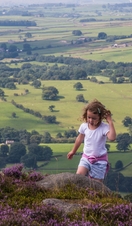 A child walking in the heather covered moors.