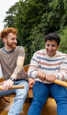 A male couple sitting in a rowboat, rowing together