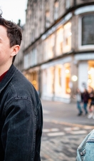 Young man and woman exploring city streets with shops in background