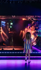A girl stands looking at a tank with jellyfish
