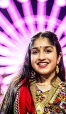 A woman celebrating Divali in front of a large lit up wheel
