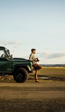 Man leaning against 4x4, holding camera