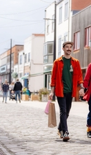 A man and a woman walk along a shopping street with bags