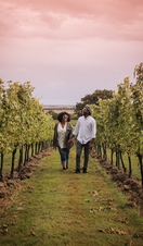 Man and woman walking between vines at a vineyard