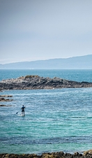 A man paddleboarding in the sea off Traigh Beach Arisaig