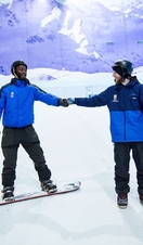 Two men skiing and snowboarding on an indoor snowslope at Chill Factore in Manchester