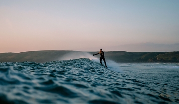 Man surfing in the evening with mountains in the distance