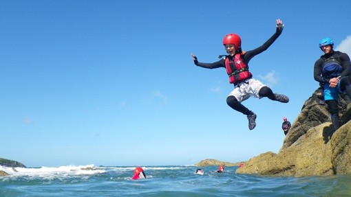 Una persona saltando al mar en una aventura de coasteering en Celtic Quest en Pembrokeshire, Gales