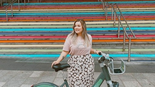 Frau mit grünem Fahrrad vor einer Treppe stehend