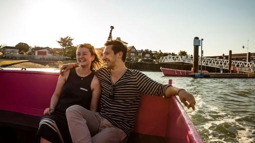 A couple seated on a bench on deck in evening sunshine