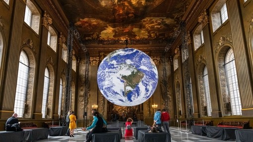 Large illuminated model of planet Earth hanging above crowd