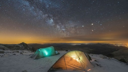 Two tents with lights inside. Snow on the ground