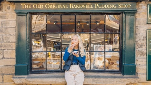 Frau genießt eine Bakewell-Tart vor einer Bäckerei