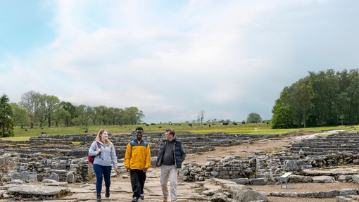 Three people walk among ancient ruins