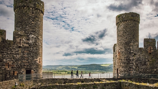 A family walking along castle walls with river view in the background