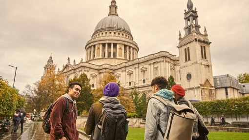 Four young people standing and talking on pavement