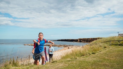 Ein kleiner Junge mit Downsyndrom spielt am Strand