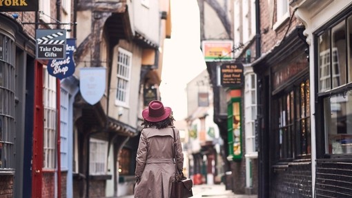 Frau mit Trenchcoat und rosa Hut beim Spaziergang