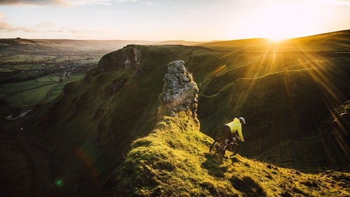 Cyclist riding down a steep glassy slope at sunset
