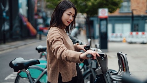 Young asian Woman Renting Bicycle From Bike Share Service