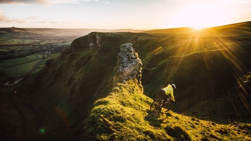 Cyclist riding down a steep glassy slope at sunset