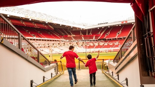 A man and boy in stadium tunnel looking out to pitch