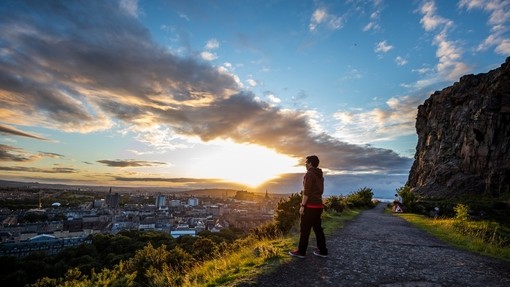 Man enjoying panoramic views of Edinburgh at the top of Arthur's Seat