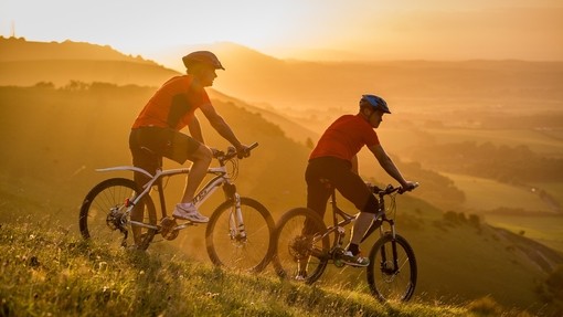 Two men on mountain bikes cycling at Devil's Dyke. Sunrise