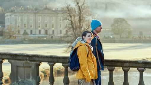 A young couple standing at the balustrade of a stone bridge