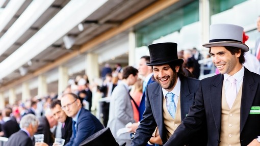 Men dressed in morning suits and top hats watching a race