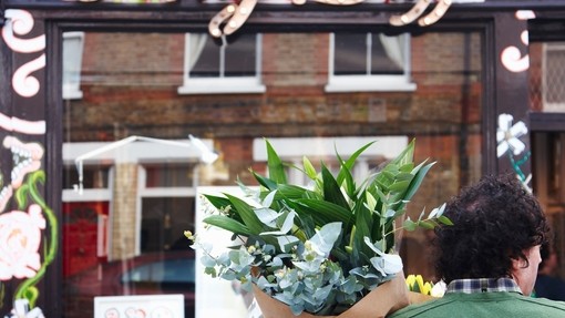 Curly haired man with fresh flowers bouquet in front of shop