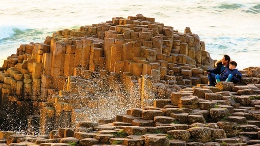 Man and boy sitting on the red basalt columns
