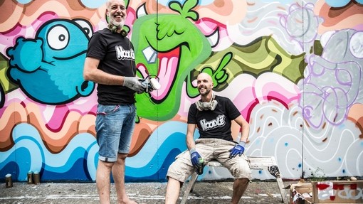 Street artists with paint cans near colourful artwork