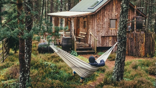 Person relaxing in hammock outside wood cabin