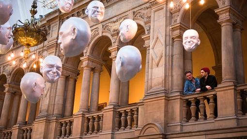 Two men looking at installation of suspended head sculptures
