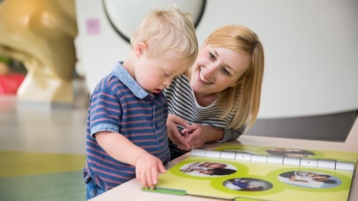 Young blonde boy with Downs Syndrome looking through a book