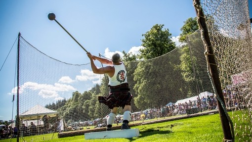 Inveraray Argyll Highland Games at Inveraray Castle. Man wearing a kilt doing the hammer throw.