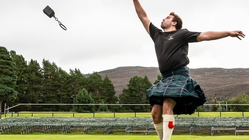 Hombre con falda escocesa lanzando pesas en Braemar Gathering, Escocia