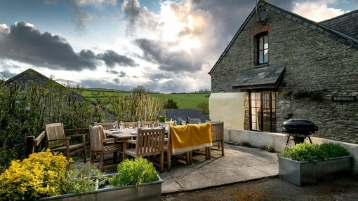 Sitzecke mit Grillkessel, Platzdeckchen und einem Teppich neben einem der Pitt Farm Holiday Cottages, Devon