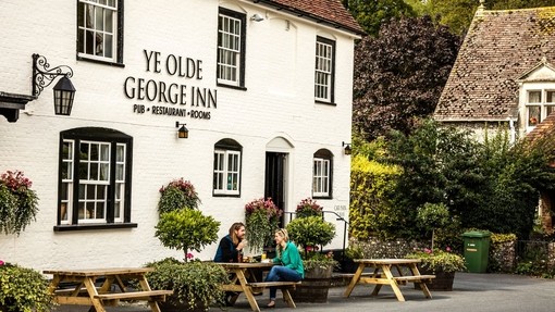 A couple sitting outside the pub on a bench having a drink