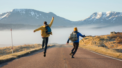 Hikers celebrating along a country road. Mountains ahead