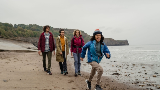 A family walking on a beach with a young boy running ahead