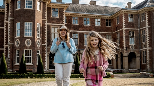 Woman and female child in front of a country house