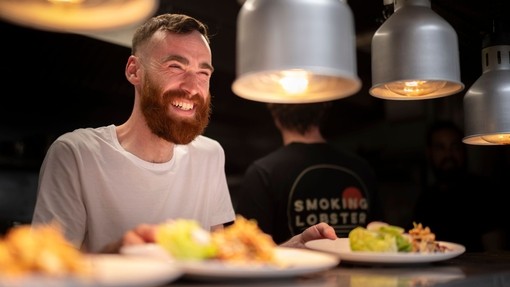 Chef smiles while preparing food in a restaurant kitchen